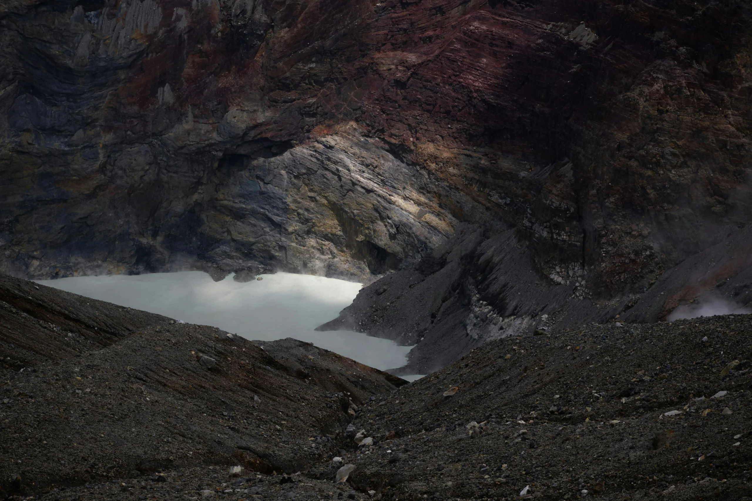 阿蘇中岳火口湖、深色岩壁與火山碎石坡