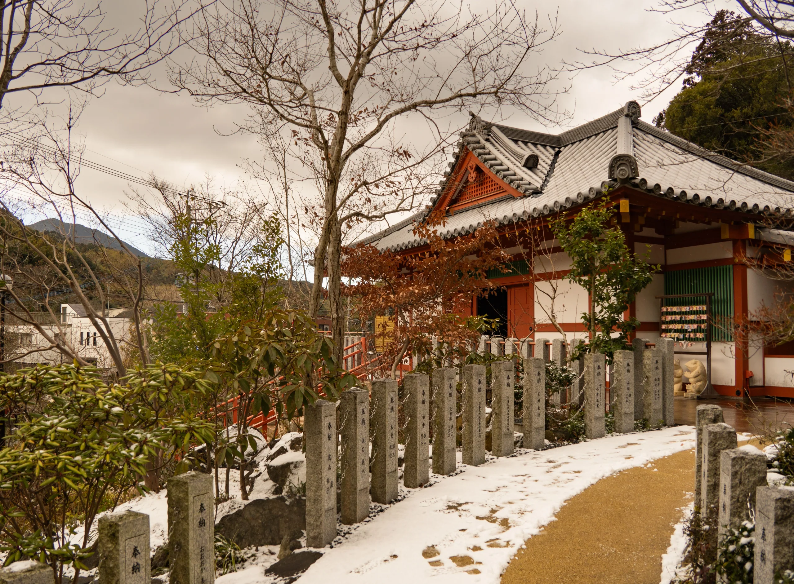 福岡寺院在冬日薄雪中的屋頂與石徑