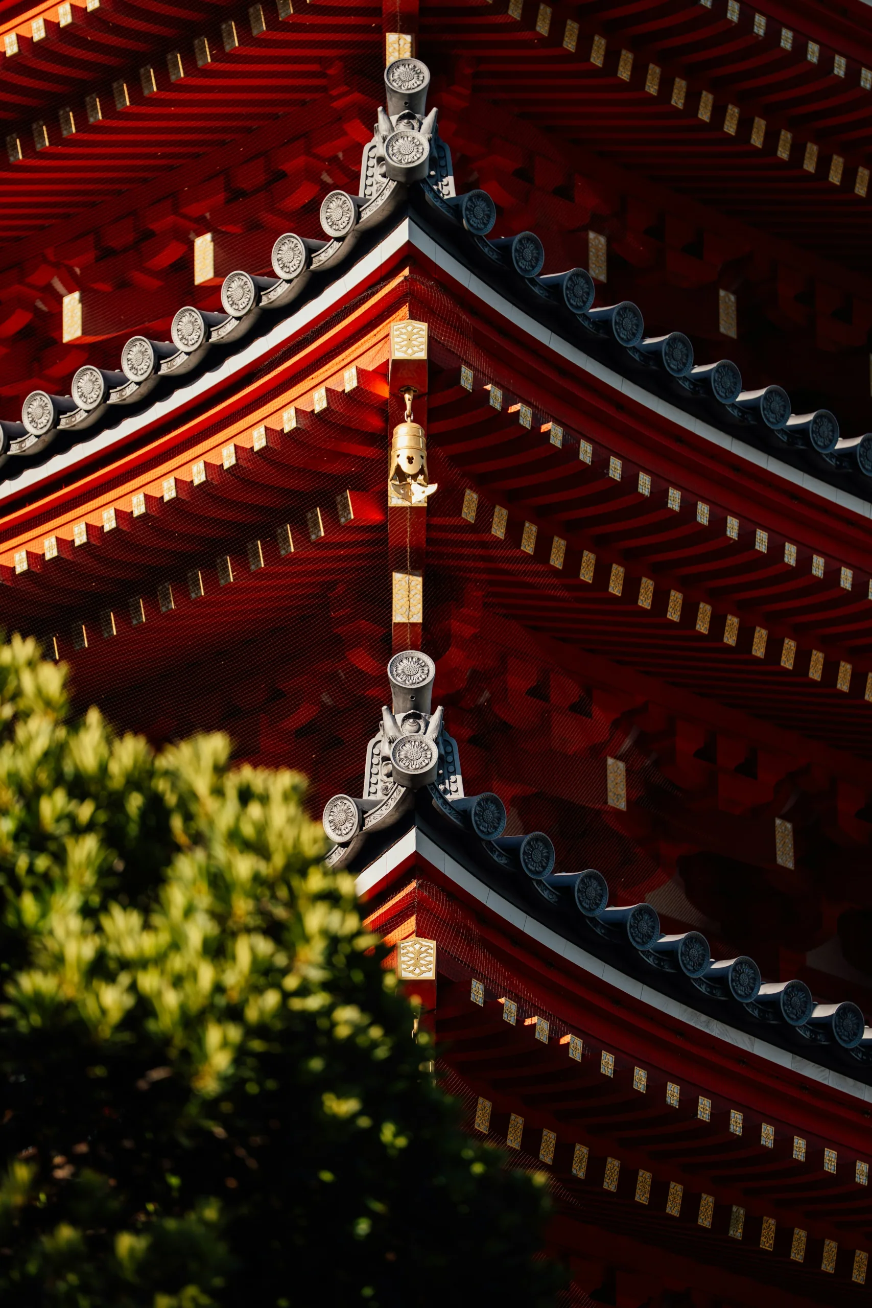 東長寺紅色瓦屋簷與金色裝飾細節，前景帶有境內樹葉