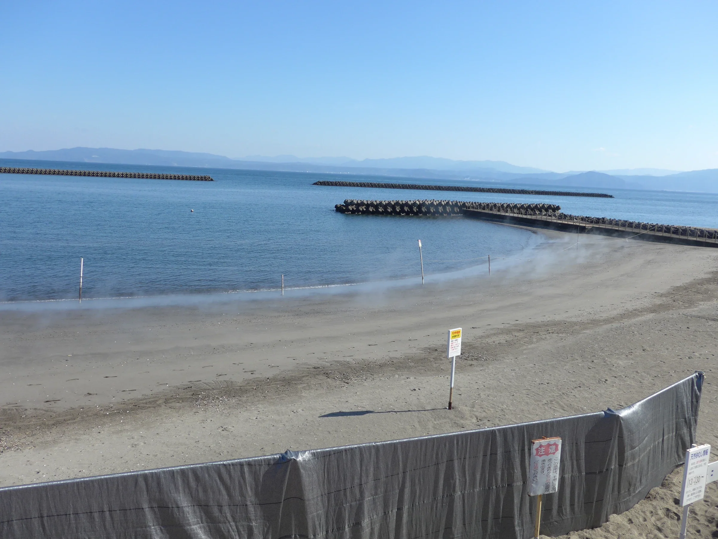 指宿砂浴海岸與海面，岸邊砂地可見地熱蒸氣