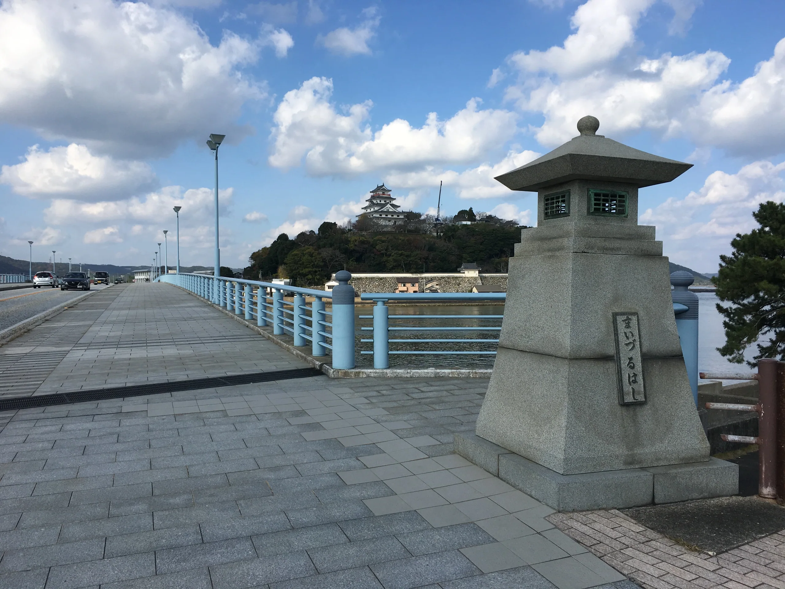 從橋面遠望唐津城與舞鶴公園，畫面包含步行接近城區的橋道，對應呼子行程後返回唐津的同日路線。