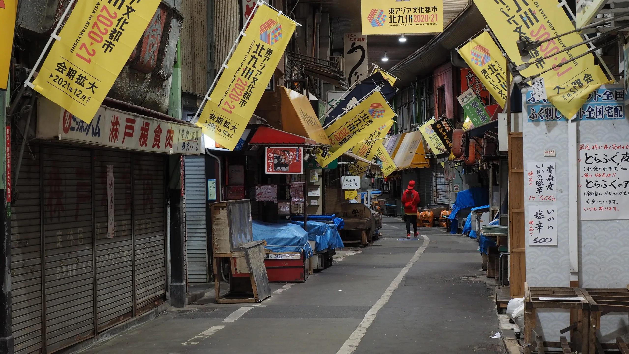 旦過市場棚頂下的狹長通道、店舖招牌與黃色旗幟