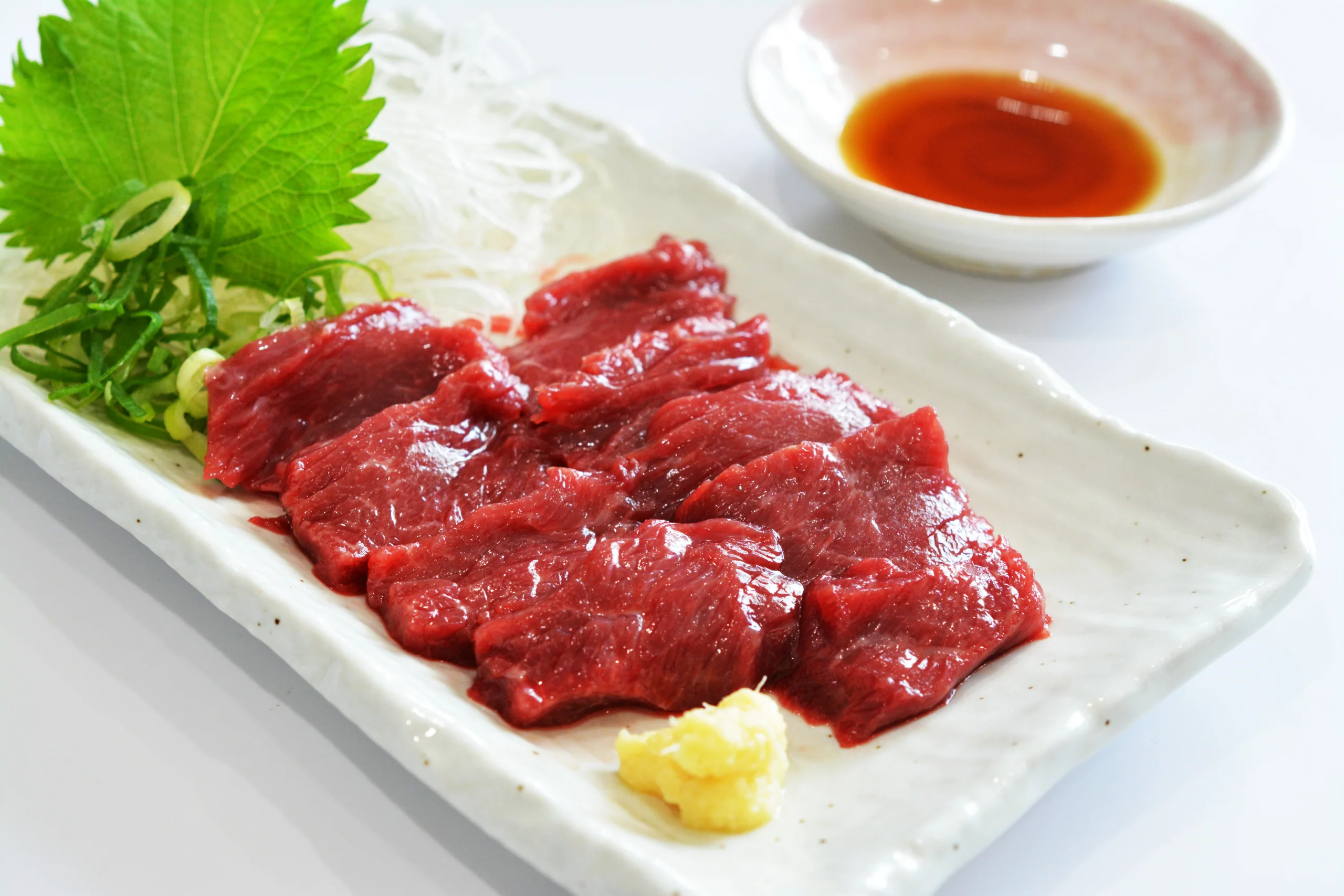 馬刺し盛合せ中的紅肉與脂紋切片，配紫蘇、蘿蔔絲和醬油