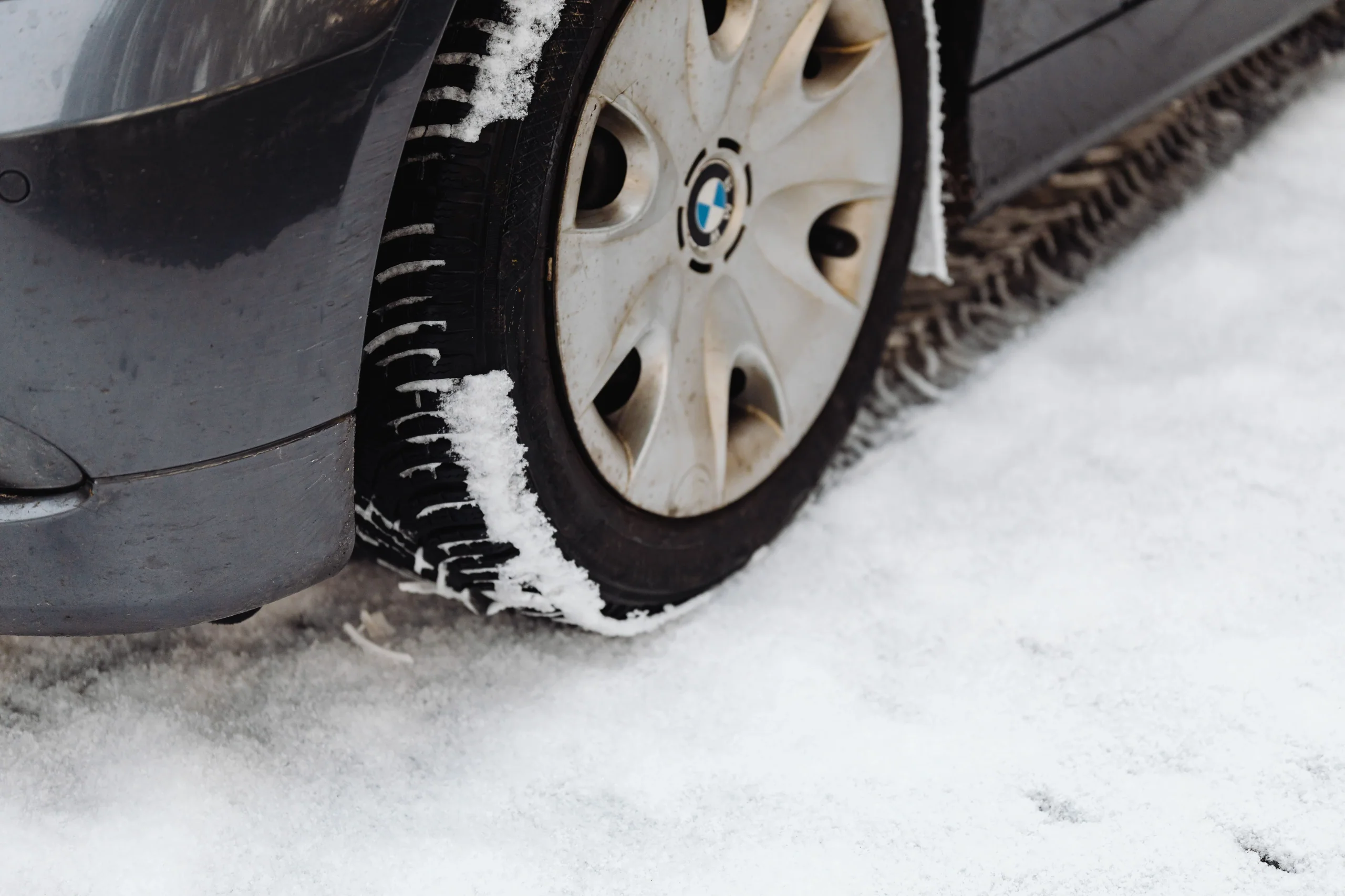 乘用車輪胎在雪地上的近照，胎面紋路沾有積雪
