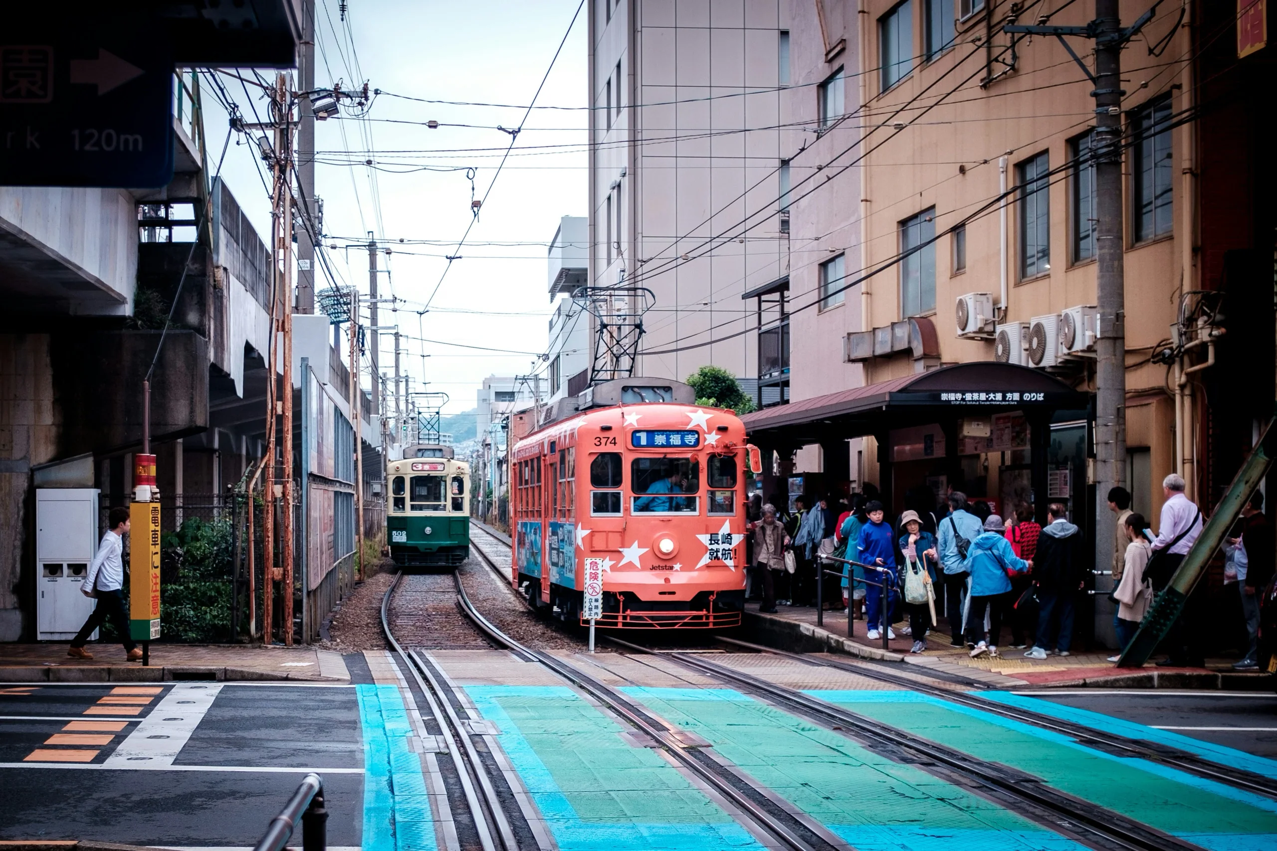 長崎市街道上的紅色路面電車與對向綠色電車