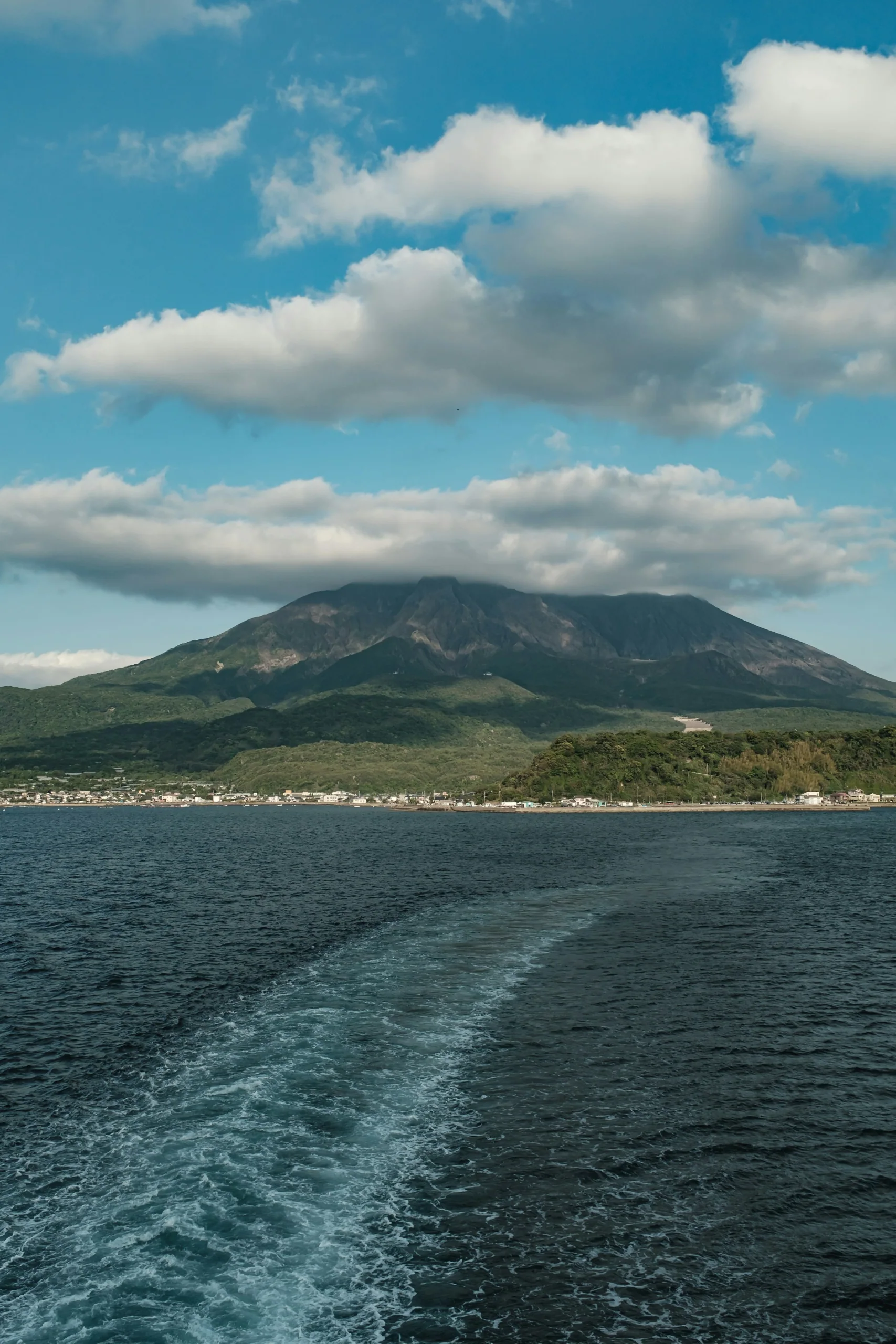 錦江灣一側遠望櫻島，海面前方是火山坡地與島岸
