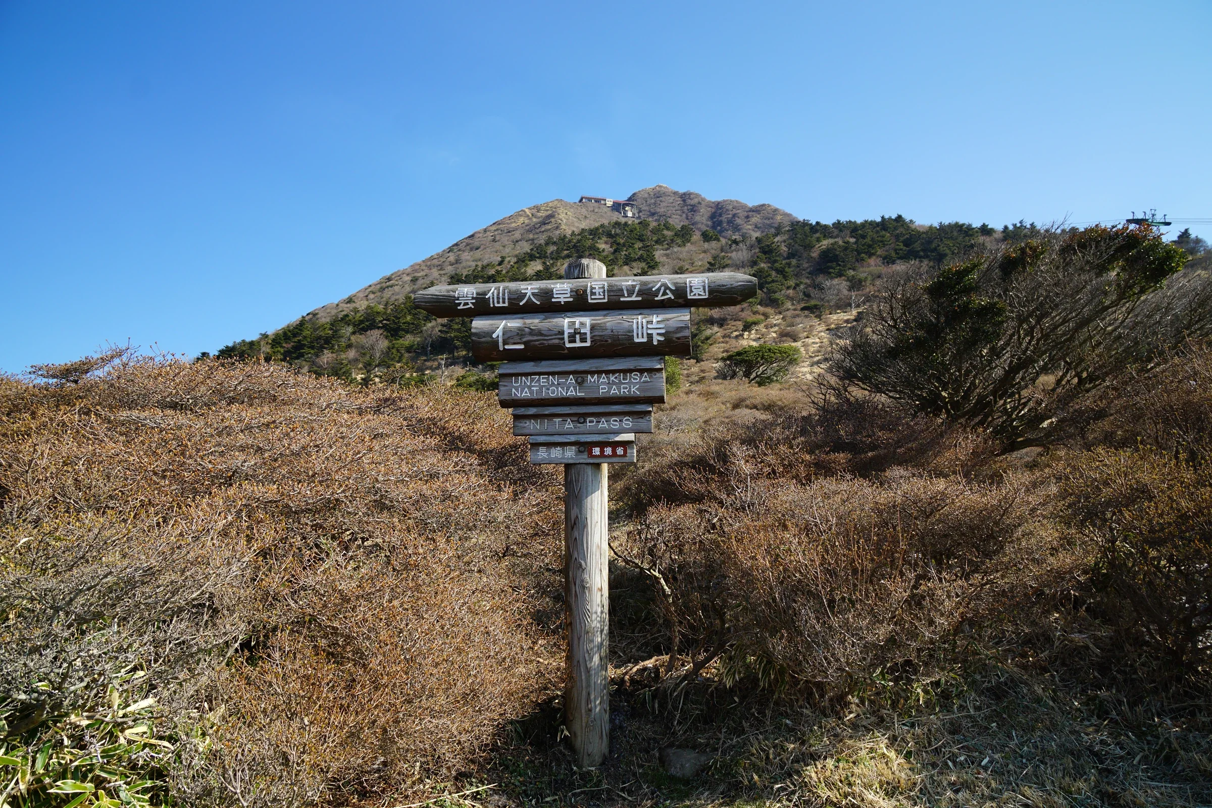 雲仙天草國立公園仁田峠標示牌，後方是山稜與樹林